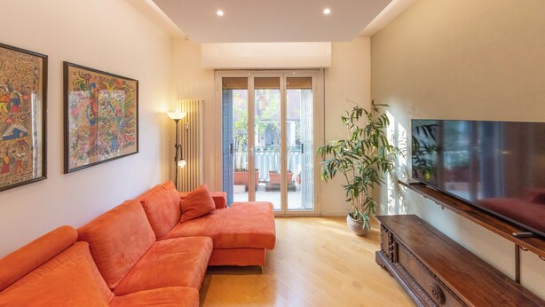 A living room with a sofa, a TV, and a plant. - HouSmart Treves 2 (Bologna)