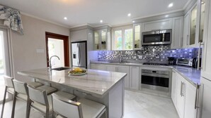 A modern kitchen with a central island, stainless steel appliances, and a tiled backsplash.