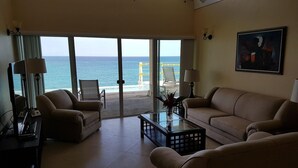 A spacious living room with a view of the ocean, furnished with a sofa, armchairs, and a coffee table. - Je Suis Jamaica - 4 B R Beachfront Villa w Staff (Duncans)
