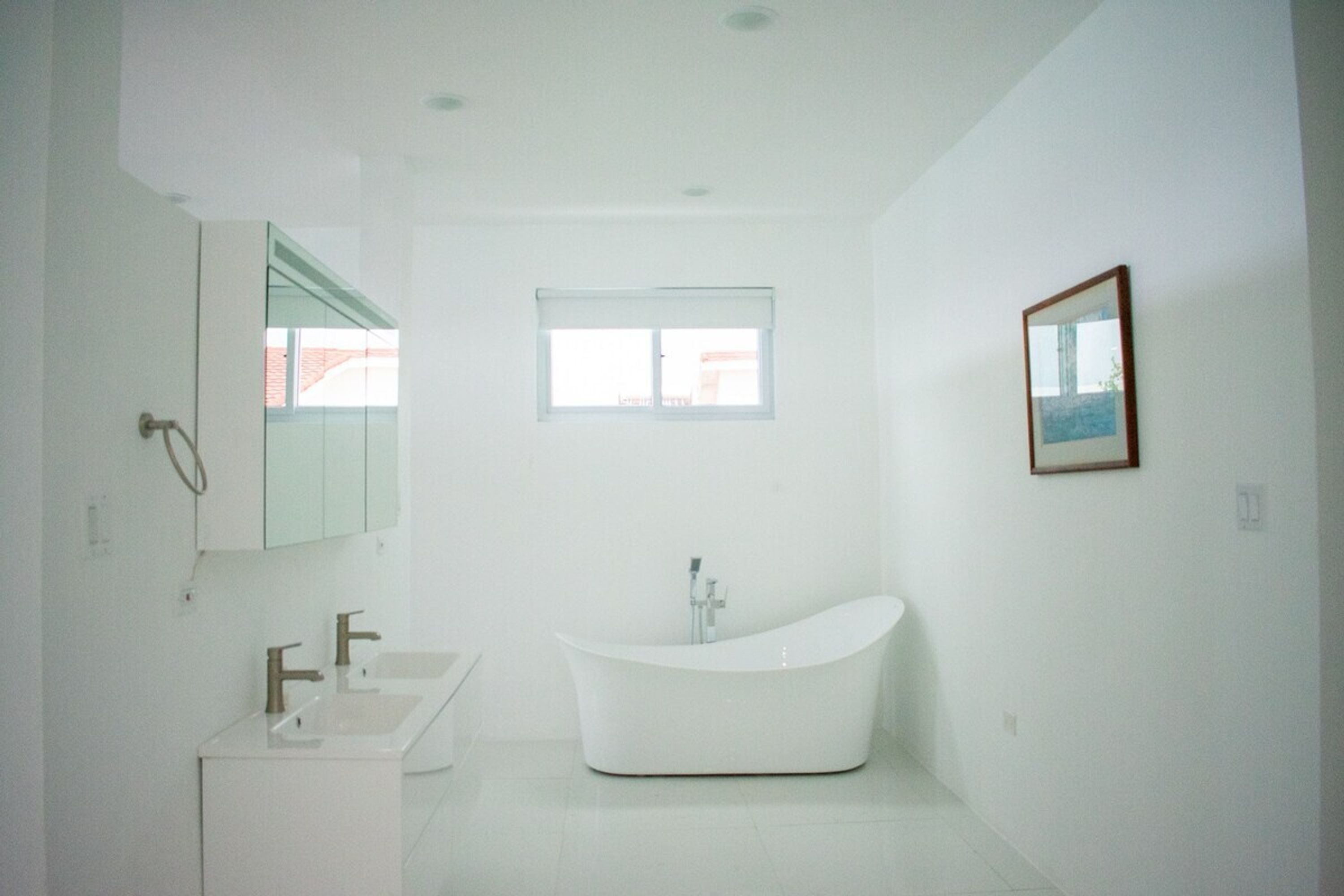 Un bagno moderno con una vasca da bagno indipendente, un mobile vanitario con specchio e una finestra che lascia entrare luce naturale.