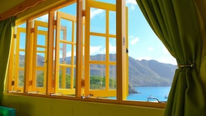 A room with a large window featuring a view of a body of water and mountains. - Turtle Point Bequia - 4 B R Villa w Staff (Bequia Island)