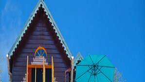 A two-story building with a balcony and a large umbrella. - Turtle Point Bequia - 4 B R Villa w Staff (Bequia Island)