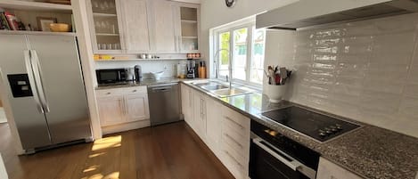 A modern kitchen with white cabinetry, stainless steel appliances, and a granite countertop.