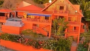 A two-story house with a balcony and a small deck area. - Flamingo Bequia - 4 B R Villa Including Cottage (Bequia Island)