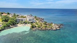 Une propriété située sur la côte, offrant une vue dégagée sur l’océan, une piscine et un rivage rocheux.
