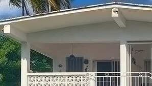 A two-story building with a balcony, a window with a decorative grille, and a door with a small window. - The Art Studio 12 Beachfront Apartment Barbados (Holetown)