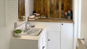 A bathroom with a wooden vanity, a sink, and a mirror. - The Art Studio 12 Beachfront Apartment Barbados (Holetown)