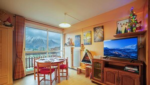 Ein gemütliches Wohnzimmer mit einem großen Fernseher, Holzmöbeln und einem Weihnachtsbaum.