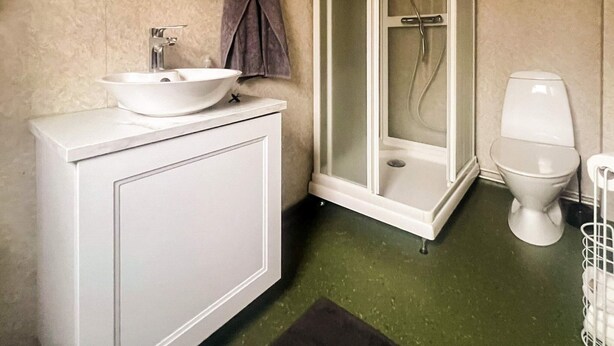 A bathroom with a white sink, a toilet, and a glass-enclosed shower. - 4 Person Holiday Home in Lonashult (Lönashult)