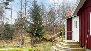 A wooden staircase leading to a red door, surrounded by a natural landscape with trees and moss. - 4 Person Holiday Home in Lonashult (Lönashult)