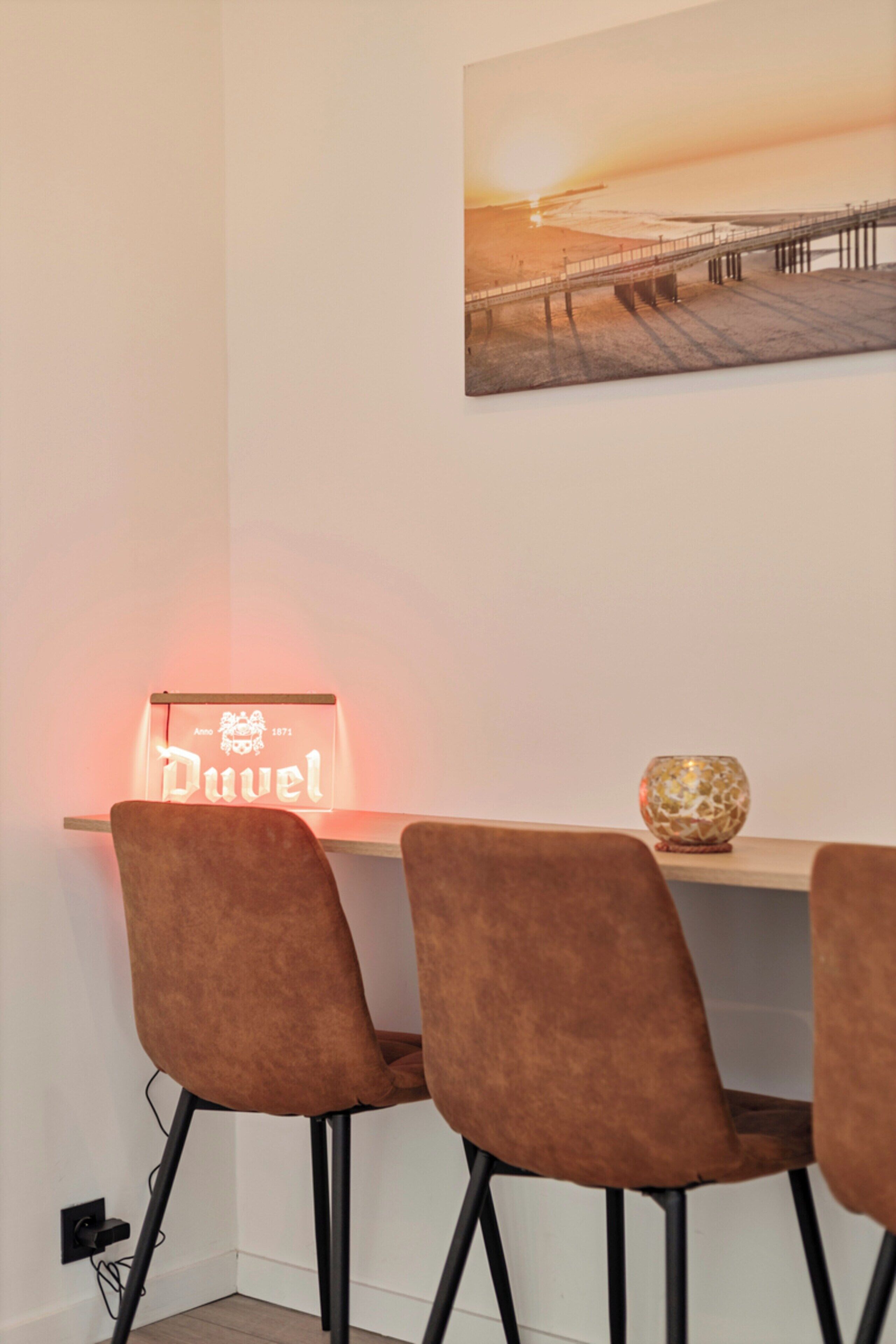 A dining area with a table, chairs, a decorative bowl, and a wall-mounted sign.