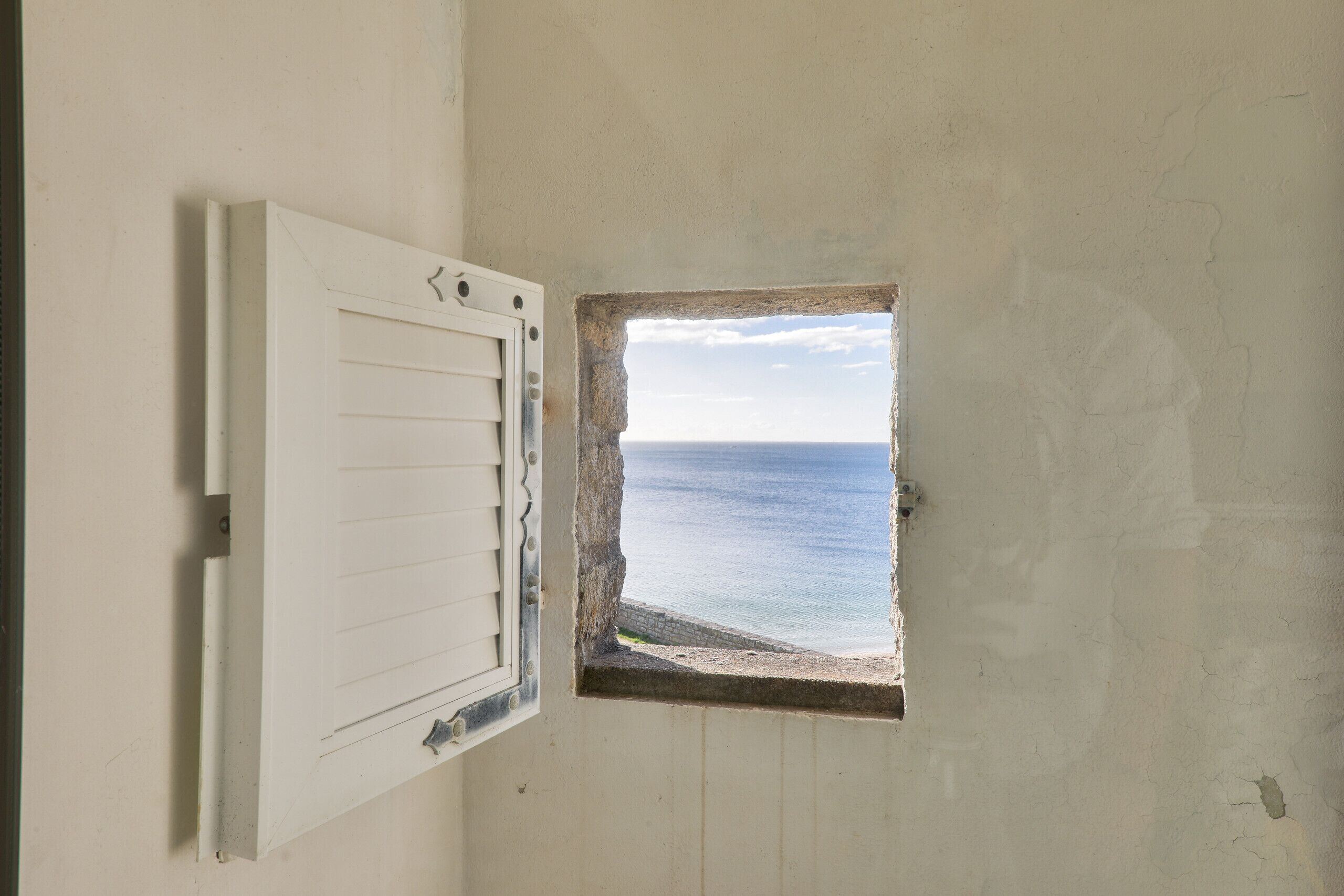 Una habitación con un ventanal pequeño que da a la playa.
