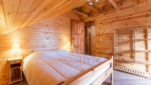 Camera da letto in una baita di legno, con un letto, comodini e un'armadio in legno.