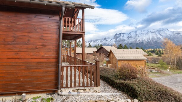 Un edificio in legno con un balcone, immerso tra montagne e foglie autunnali.