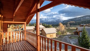 Un balcone in legno con vista su montagne innevate e un villaggio sottostante.