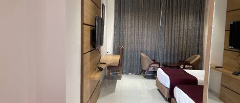 A modern hotel room with two beds, a desk, a chair, a TV, and a curtain.