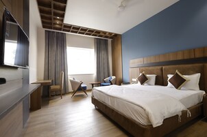 Una habitación de hotel moderna con una cama grande, un escritorio, una silla y un televisor.