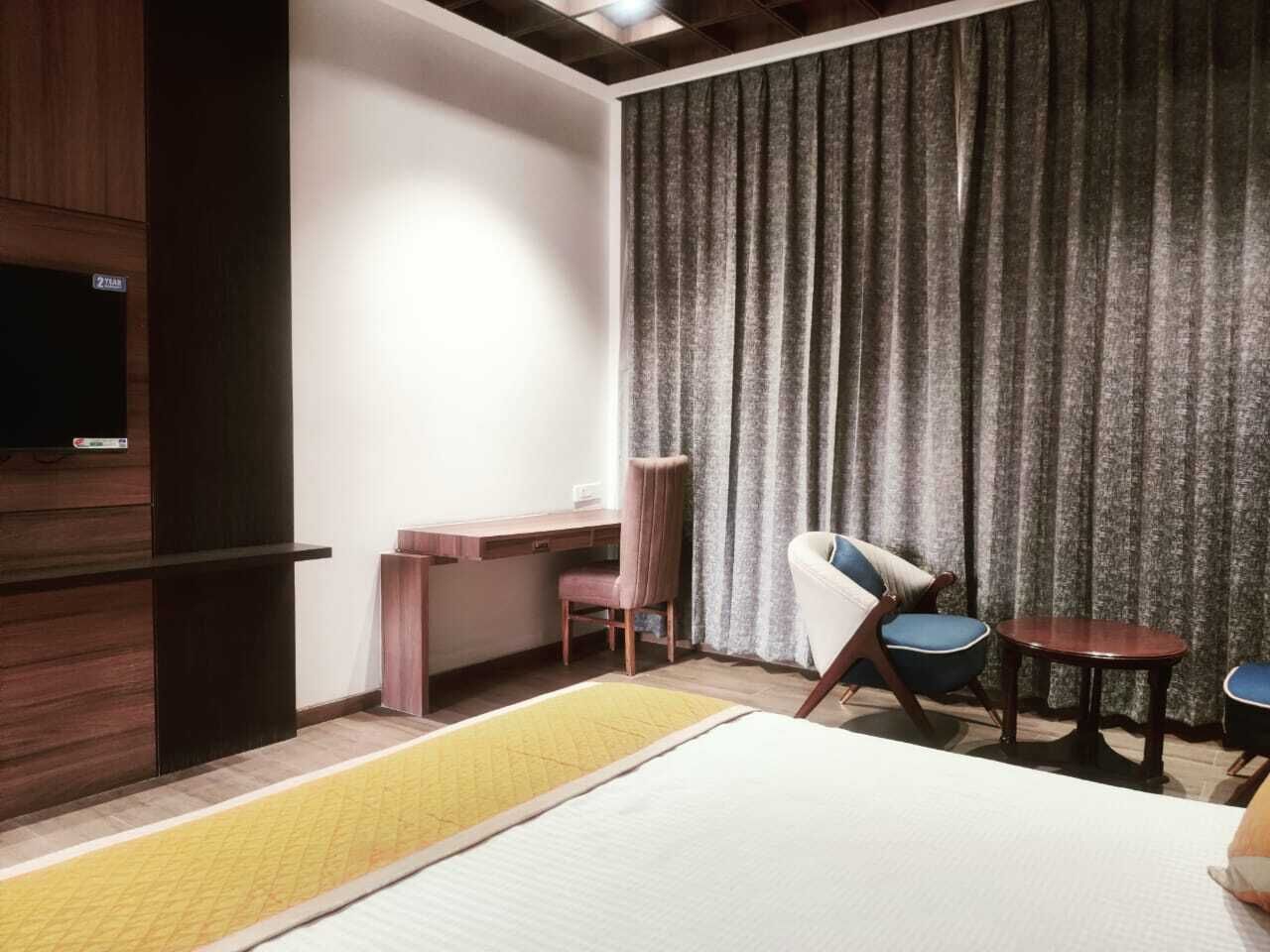 Une chambre d’hôtel équipée d’un lit, d’un bureau, d’une chaise et d’un téléviseur fixé au mur.