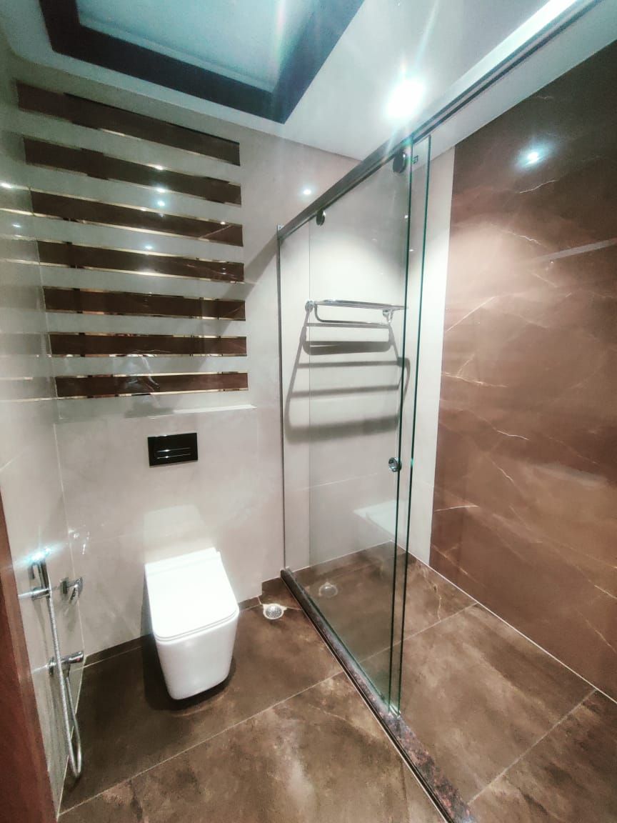 Un baño moderno con cabina de ducha de vidrio, inodoro blanco y toallero.