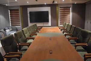 Una sala de conferencias con una larga mesa, varias sillas, un sofá y un televisor de pantalla plana grande en la pared.