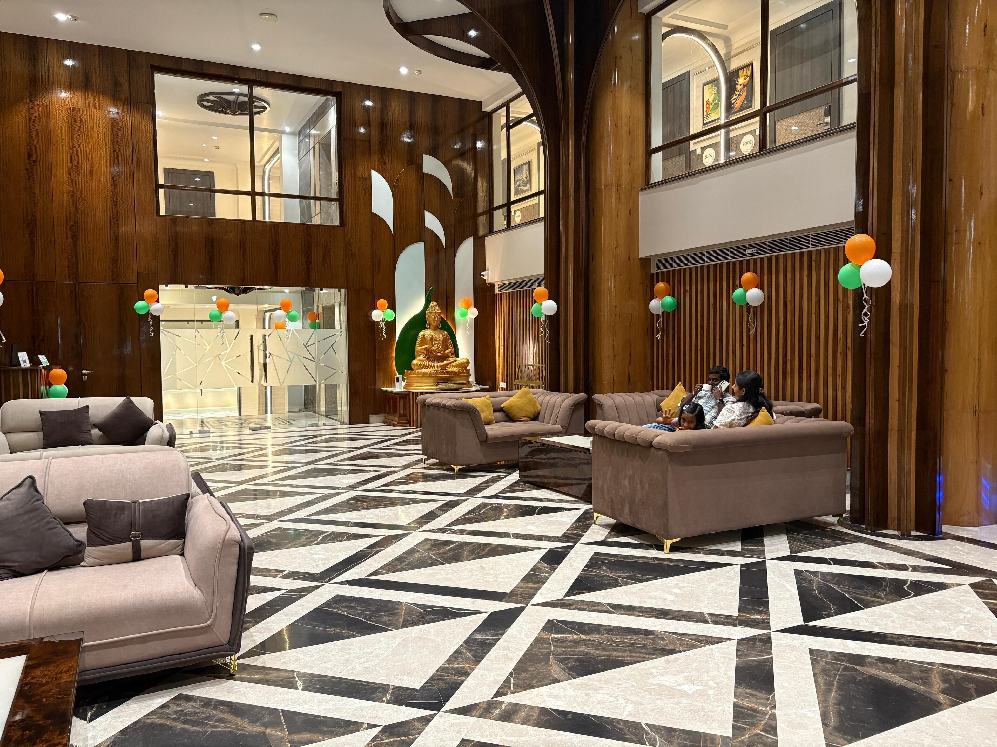 A spacious lobby with modern furnishings, a Buddha statue, and a reception desk.