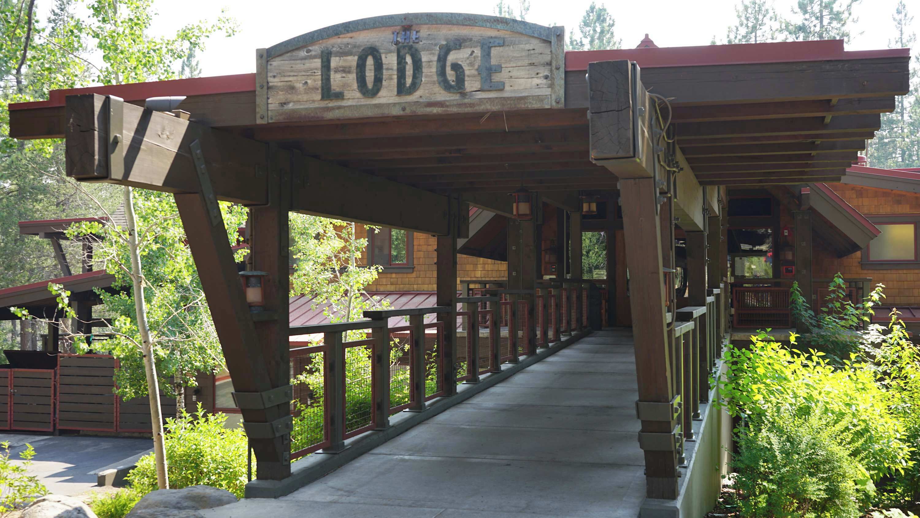 A wooden covered walkway leading to a lodge with a sign that reads "Lodge".