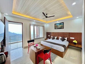 Una moderna camera d'hotel con un letto grande, una scrivania e un balcone con vista sulle montagne.