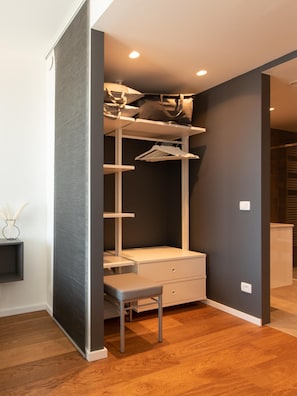 A compact walk-in closet with a bench, shelves, and hanging space. - Central Apartment in Ostend Near Beach (Ostend)