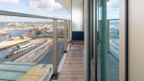 A balcony with a view of a river and train tracks, a wooden floor, and a blue chair. - Central Apartment in Ostend Near Beach (Ostend)