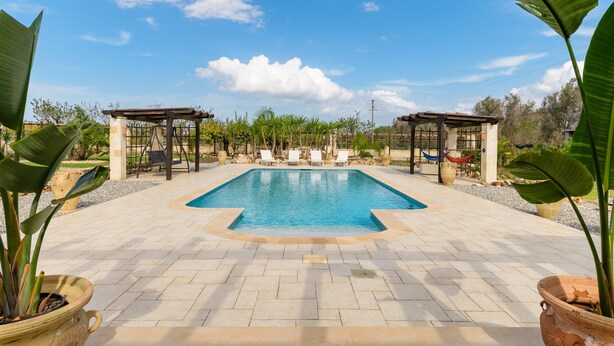 A rectangular swimming pool with a tiled deck, surrounded by potted plants and a pergola structure. - Villa Alexander con Piscina by Wonderful Italy (San Vito dei Normanni)