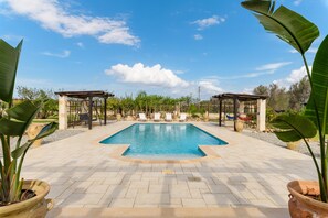 A rectangular swimming pool with a tiled deck, surrounded by potted plants and a pergola structure. - Villa Alexander con Piscina by Wonderful Italy (San Vito dei Normanni)