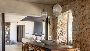 A dining area with a stone wall, wooden table, and chairs.
