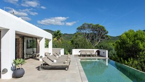A modern outdoor pool area with lounge chairs and a clear view of the surrounding landscape.