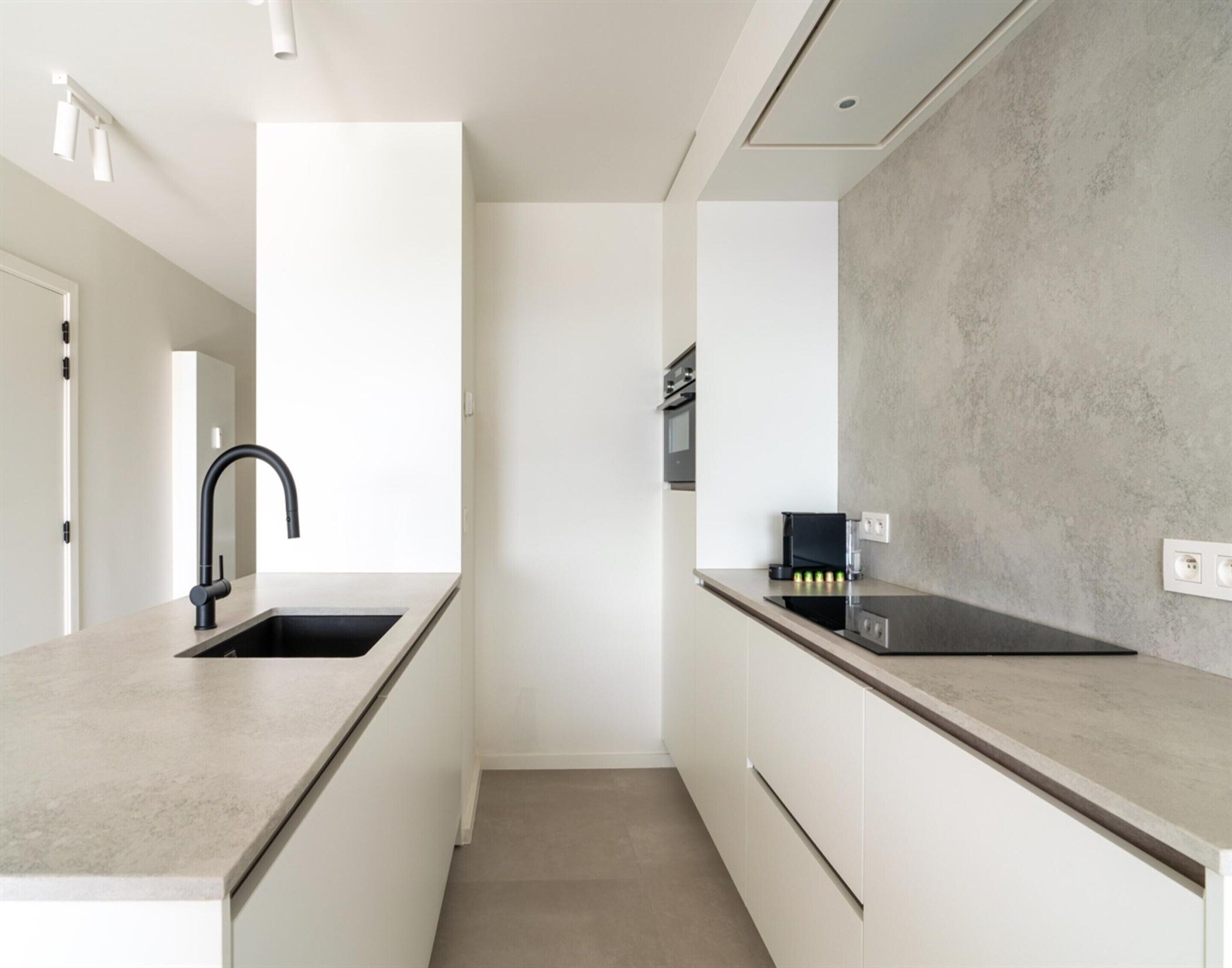 A modern kitchen with a sink, countertop, and built-in oven.
