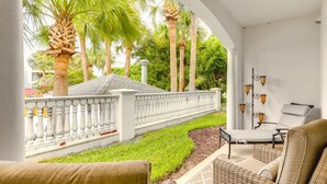 Un espace extérieur aménagé avec des meubles en osier, une rambarde blanche et des palmiers.