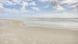 Une plage avec un large rivage sablonneux et des vagues douces.