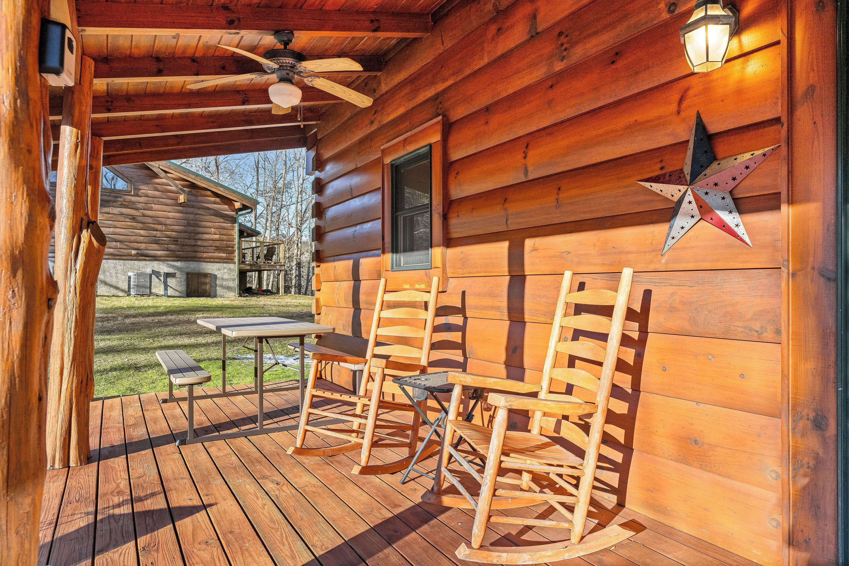 A wooden cabin with a porch, rocking chairs, a table, and a star decoration.