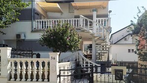 Ein mehrstöckiges Gebäude mit Balkon, Treppe und Baum davor.