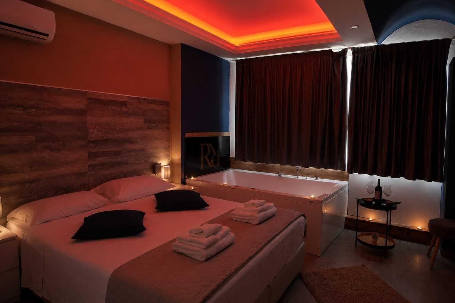 A modern hotel room with a large bed, a bathtub, and a window with curtains.