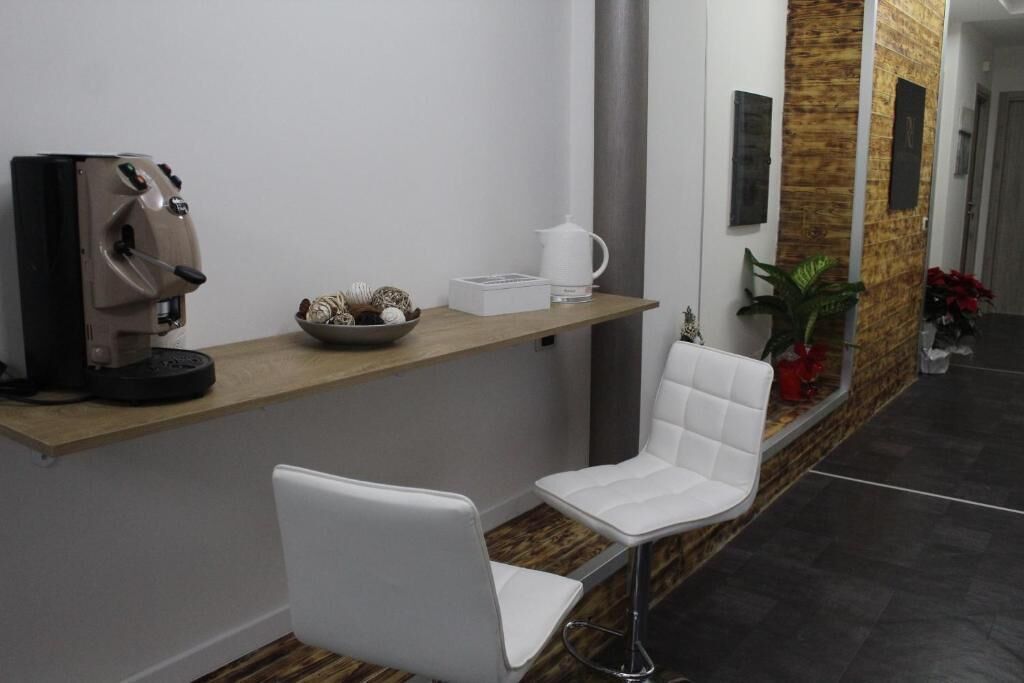 Un área de recepción con una máquina de café, un cuenco de objetos decorativos y una silla blanca.