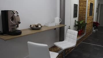 Un área de recepción con una máquina de café, un cuenco de objetos decorativos y una silla blanca.