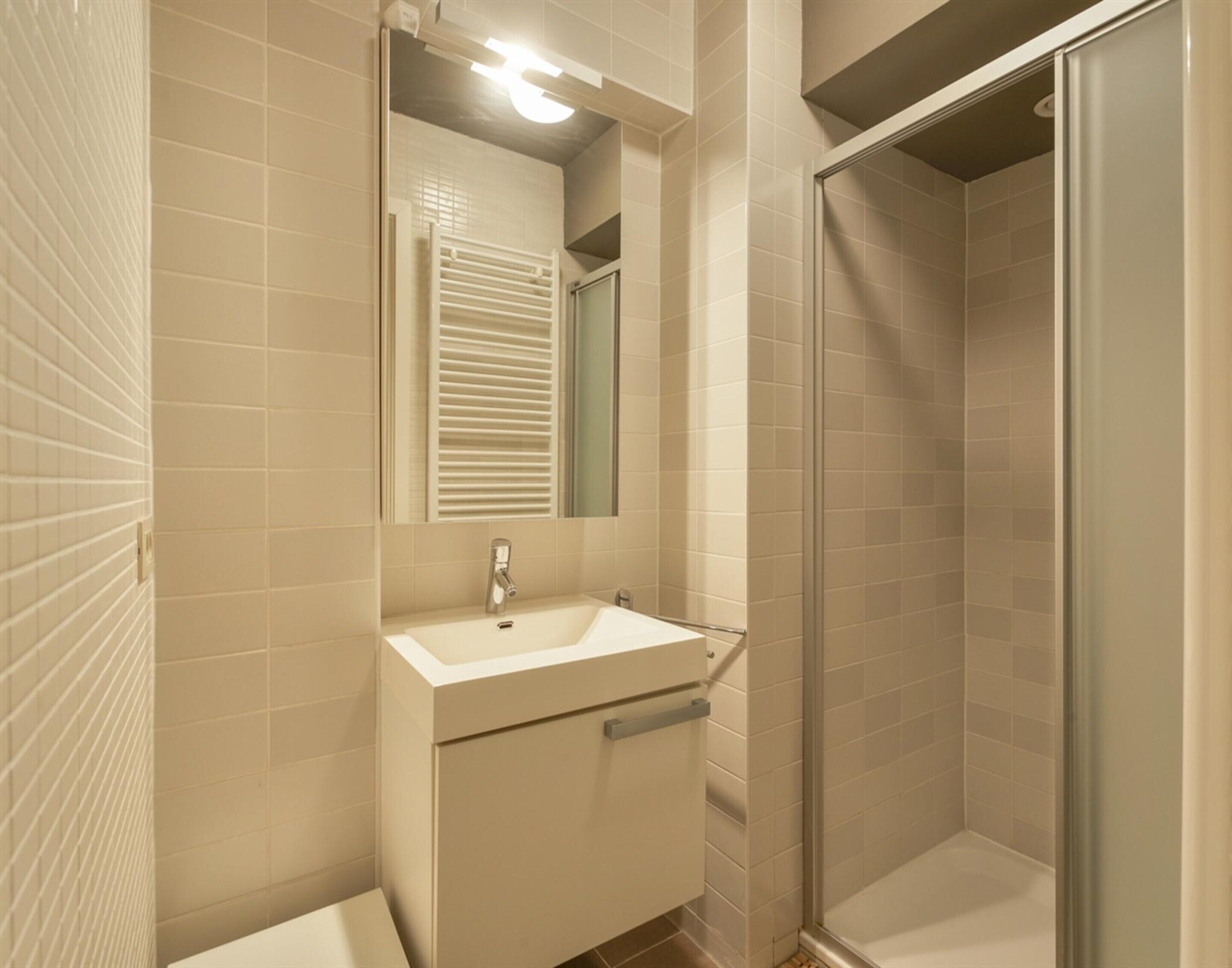 Une salle de bain équipée d’un lavabo, d’un miroir et d’une douche à parois en verre.