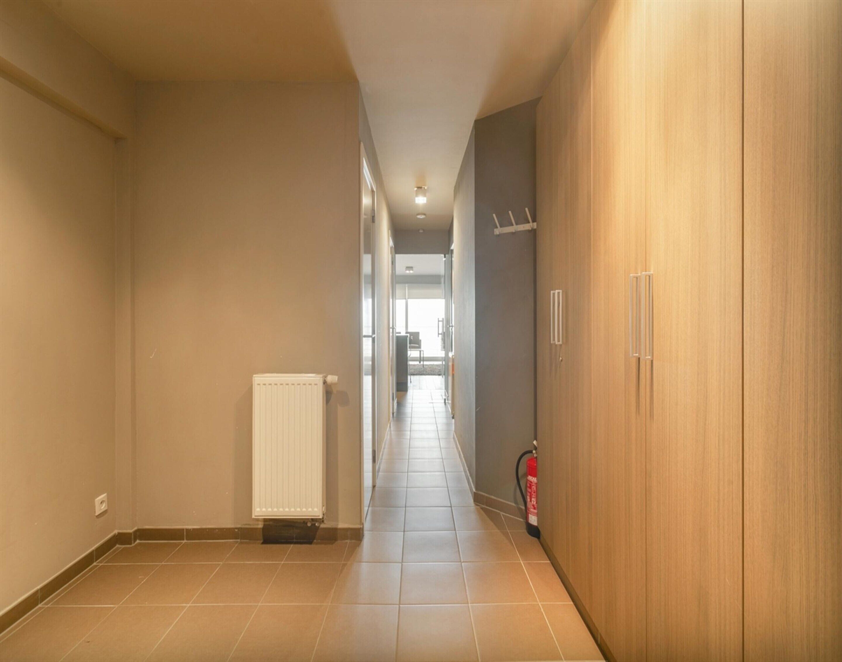 En hall med ett element, en brandsläckare och en garderob i trä.