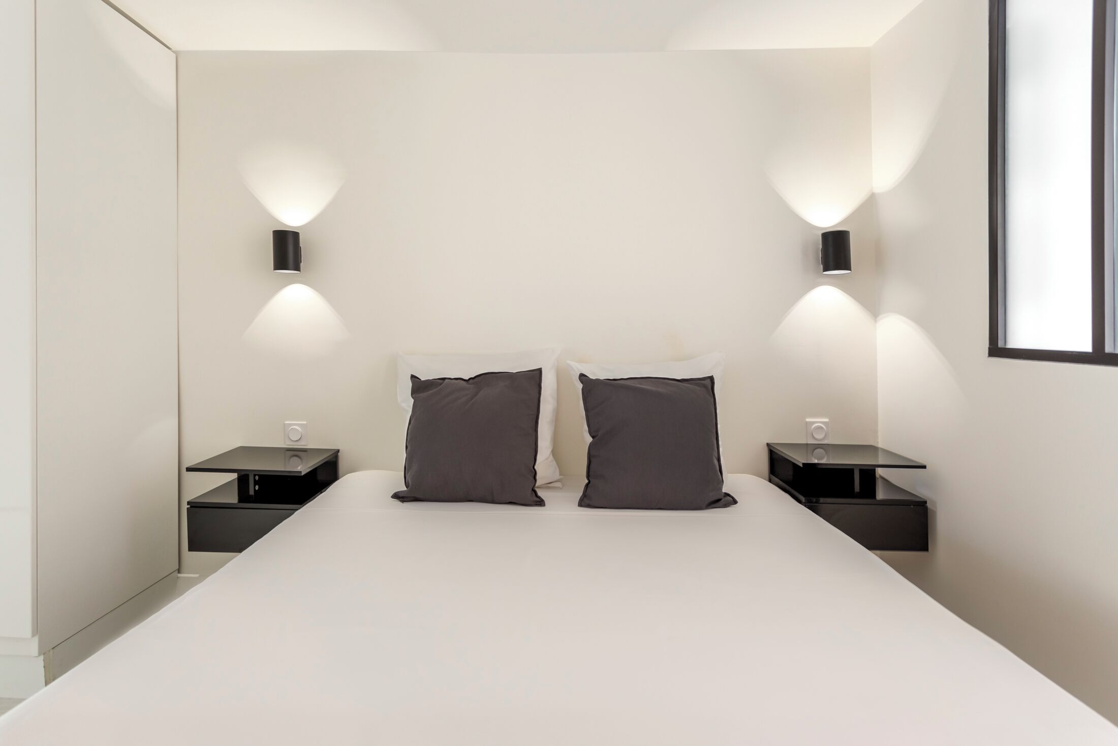 Un dormitorio moderno con una cama grande, dos mesitas de noche e iluminación empotrada.