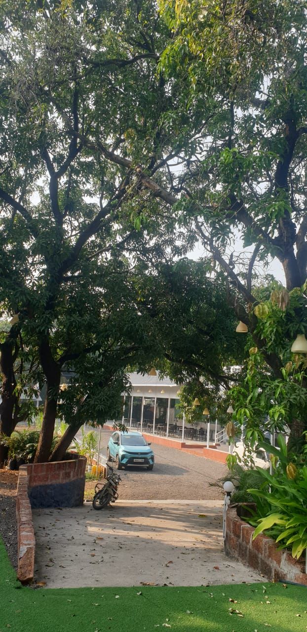 Un chemin pavé mène à un bâtiment doté d’une entrée abritée, qui est entouré d’arbres et de verdure.