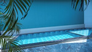 A swimming pool with a tiled floor and walls, surrounded by palm trees. - Natures Cove Resort  (Alibag)