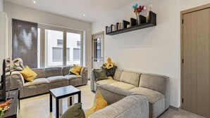 A modern living room with two grey sofas, a coffee table, and a bookshelf with decorative items. - Apartment in Blankenberge Near Sea Dyke (Blankenberge)