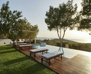 An infinity pool with lounge chairs and a deck, surrounded by trees and a view of the sea. - Luxury Villa With sea and Sunsets Views (Nijar)