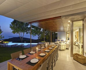 An outdoor dining area with a long wooden table set for a meal, surrounded by wicker chairs. - Luxury Villa With sea and Sunsets Views (Nijar)