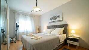 A neatly arranged bedroom with a bed, bedside tables, a lamp, and a painting on the wall.